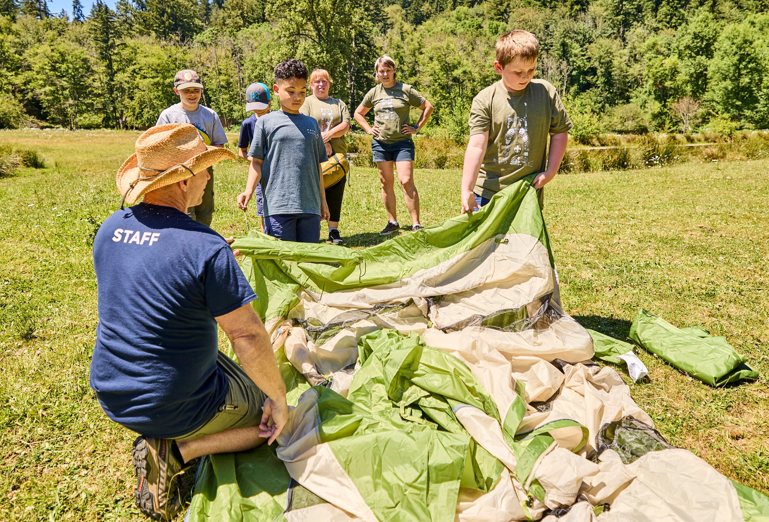 Scouts and leaders setting up camp outdoors.