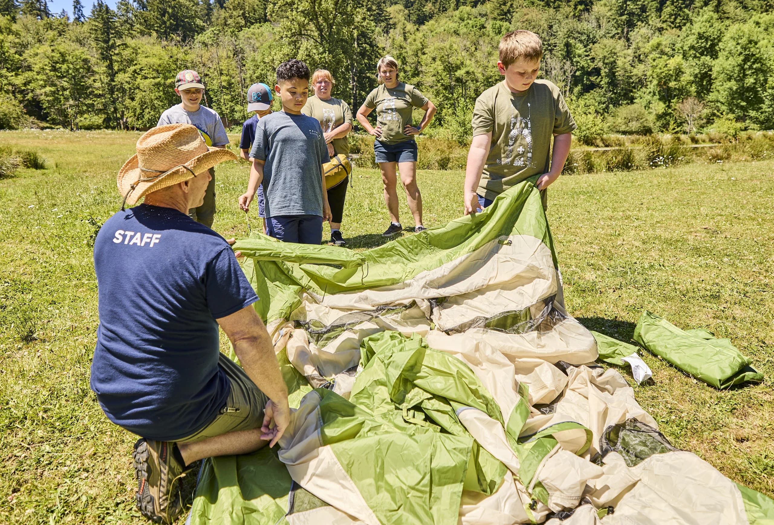 Scouts and leaders setting up camp outdoors.